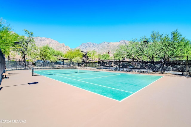 view of tennis court with a mountain view and basketball hoop