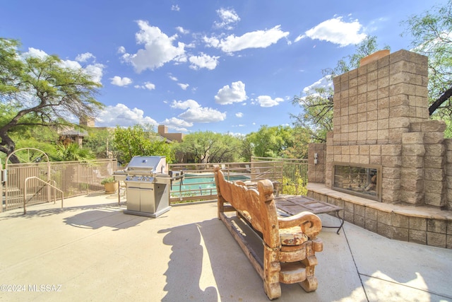 view of patio featuring an outdoor stone fireplace and area for grilling