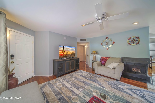 living room featuring ceiling fan and dark wood-type flooring