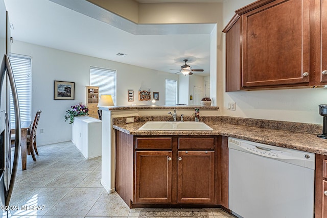 kitchen with dishwasher, sink, ceiling fan, light tile patterned floors, and kitchen peninsula