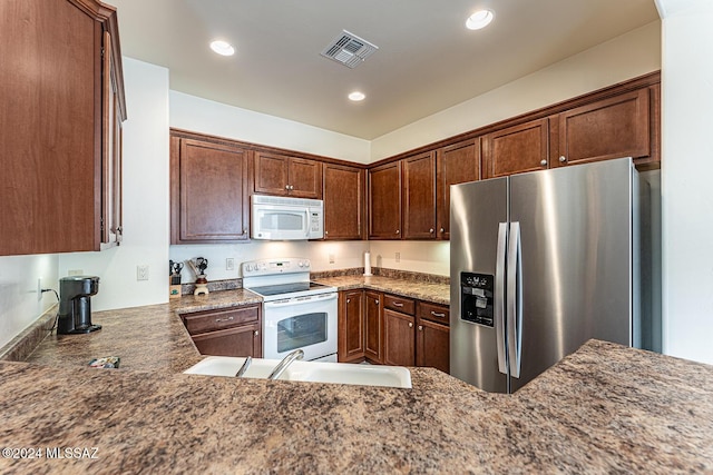 kitchen with sink, dark stone counters, and white appliances