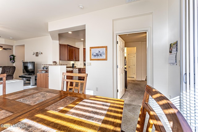 carpeted dining area with ceiling fan