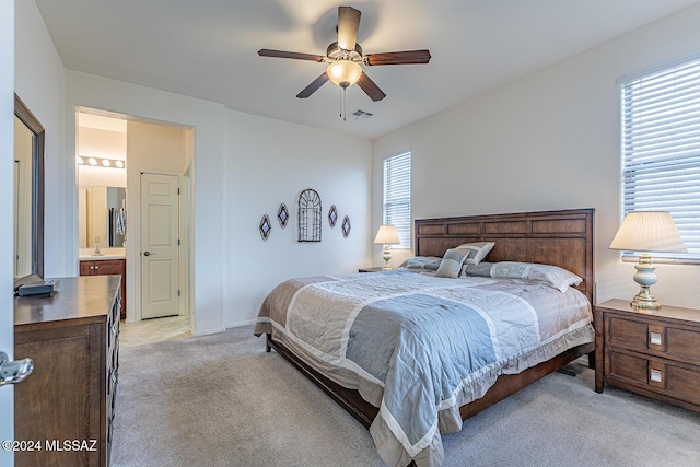 carpeted bedroom with ensuite bathroom, ceiling fan, and sink