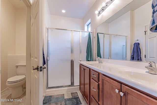 bathroom with vanity, toilet, and a shower with door