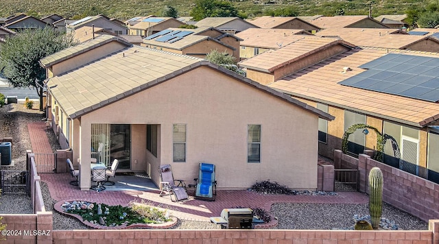 rear view of property featuring central AC unit, solar panels, and a patio area