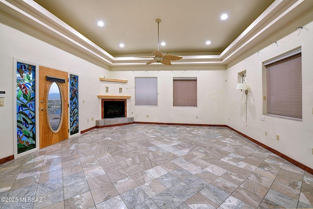 unfurnished living room with ceiling fan and a tray ceiling