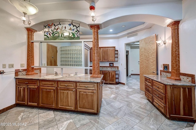 bathroom with a raised ceiling, vanity, and ornate columns