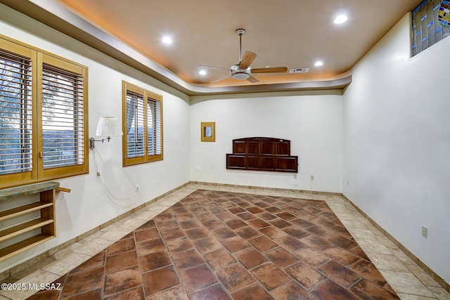 unfurnished room with ceiling fan and a tray ceiling