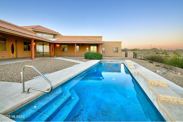 pool at dusk featuring a patio