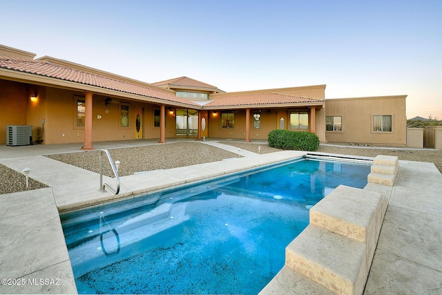 pool at dusk with a patio and central AC