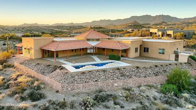 back house at dusk featuring a patio area and a mountain view