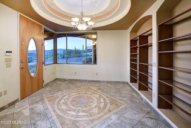 entrance foyer with an inviting chandelier, a mountain view, and a tray ceiling