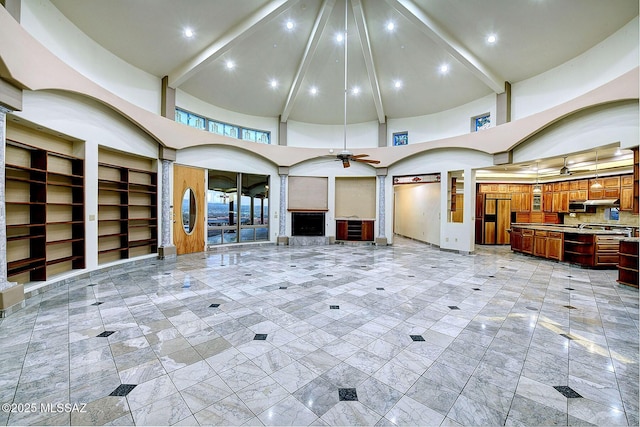 unfurnished living room featuring ceiling fan, beamed ceiling, and a towering ceiling