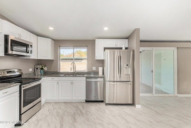 kitchen featuring white cabinetry, appliances with stainless steel finishes, sink, and dark stone counters