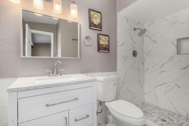 bathroom with vanity, toilet, and a tile shower