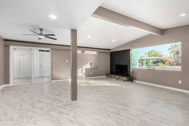 unfurnished living room featuring a fireplace, lofted ceiling with beams, and ceiling fan