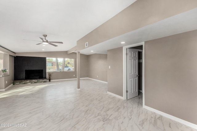 basement with ceiling fan and a fireplace