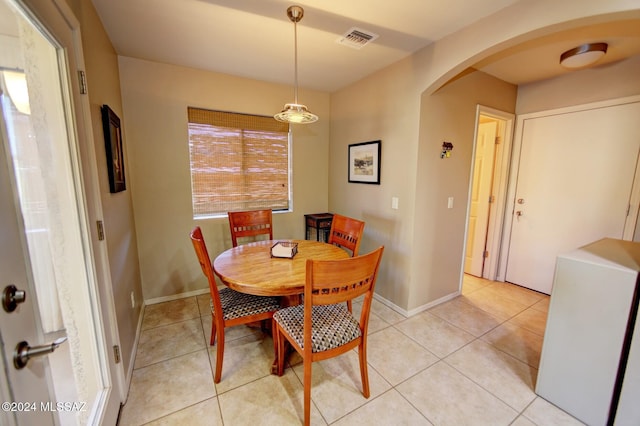 dining area featuring light tile patterned floors, visible vents, arched walkways, and baseboards