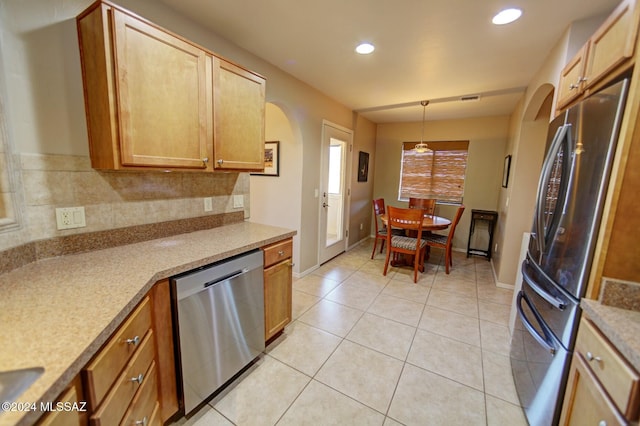 kitchen with light tile patterned floors, stainless steel appliances, arched walkways, and decorative backsplash