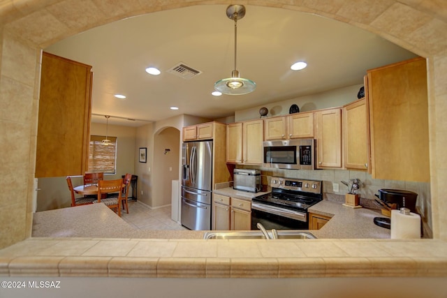 kitchen featuring visible vents, light brown cabinetry, a sink, stainless steel appliances, and arched walkways