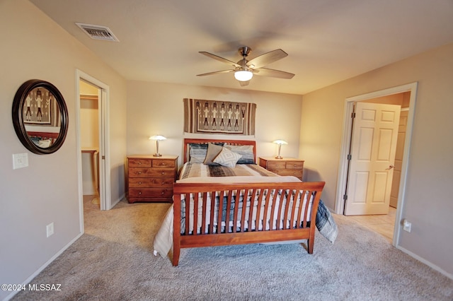 carpeted bedroom with visible vents, a ceiling fan, a walk in closet, and baseboards