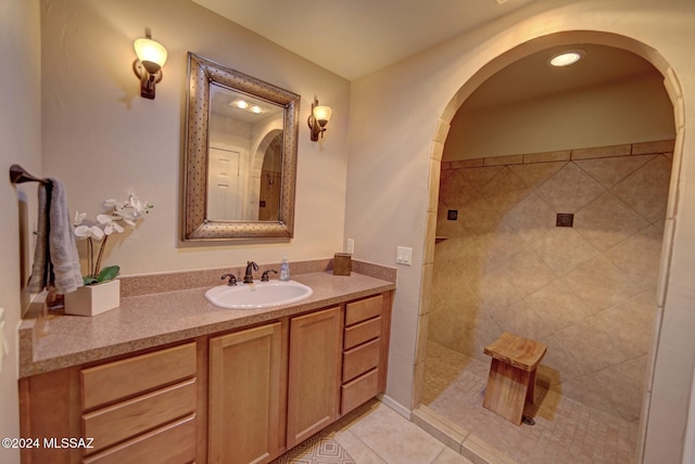 bathroom with tile patterned flooring, tiled shower, and vanity