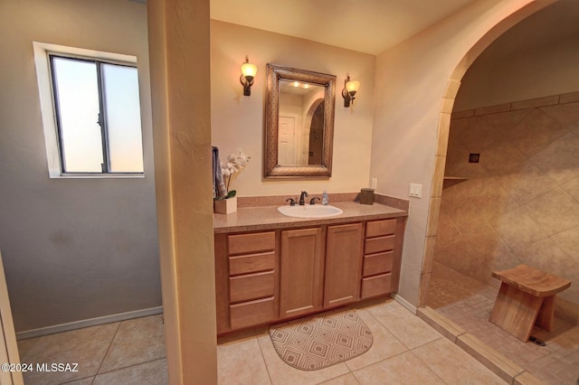 bathroom featuring tile patterned flooring, vanity, baseboards, and a walk in shower