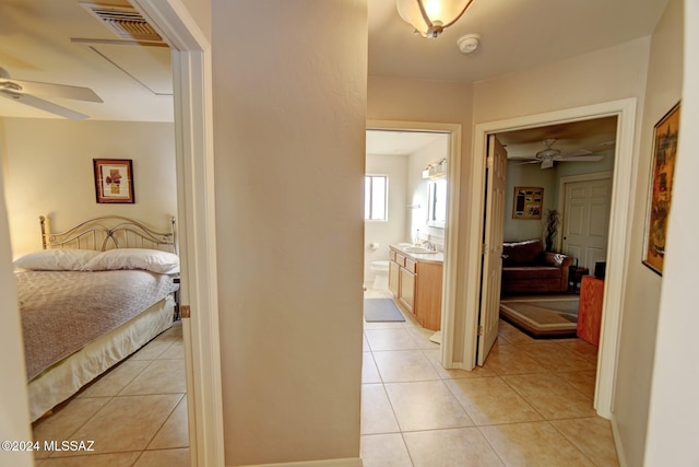 hallway with light tile patterned floors, visible vents, and a sink