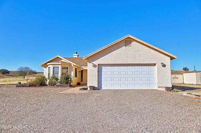 single story home featuring stucco siding, a garage, and gravel driveway