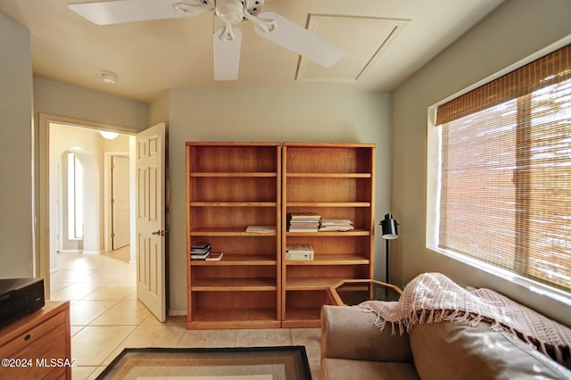 living area featuring light tile patterned floors, attic access, and a ceiling fan