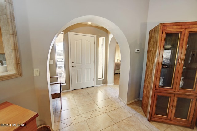 entryway featuring light tile patterned floors, baseboards, and arched walkways