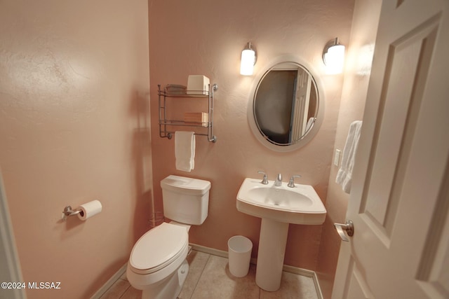 half bath featuring tile patterned flooring, toilet, baseboards, and a sink