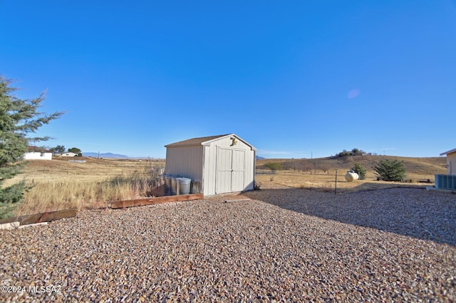 view of yard featuring an outdoor structure, a storage unit, and central AC unit