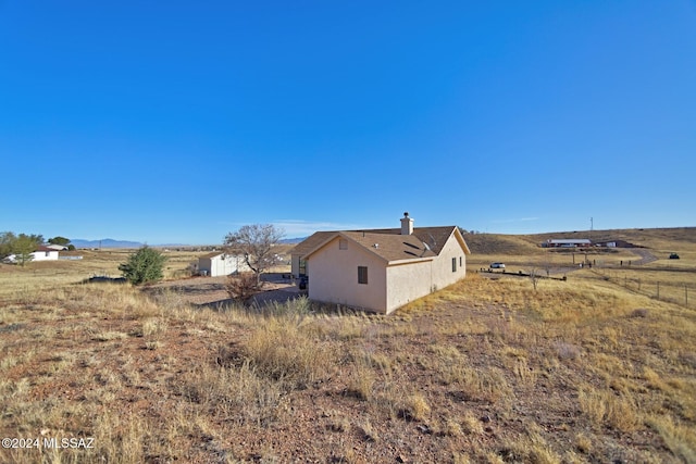 view of property exterior with a rural view and stucco siding