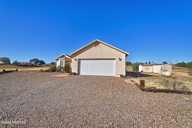 ranch-style home featuring stucco siding, gravel driveway, and a garage