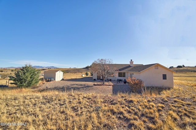 exterior space with stucco siding, a rural view, an outdoor structure, and a shed