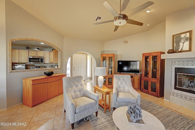 living area featuring visible vents, light tile patterned floors, a tile fireplace, arched walkways, and a ceiling fan