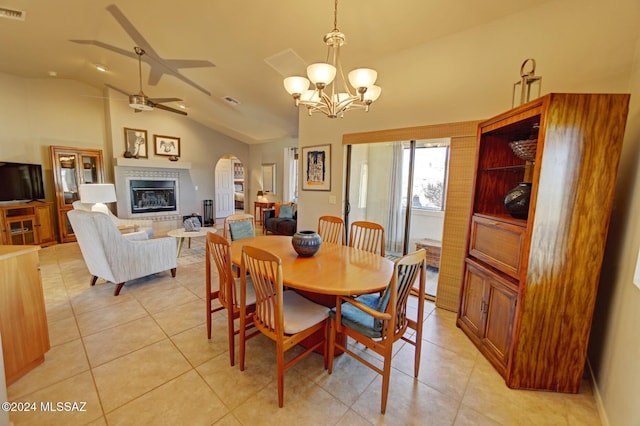 dining space with a glass covered fireplace, lofted ceiling, light tile patterned flooring, and arched walkways