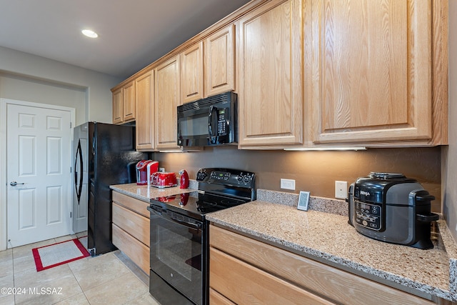 kitchen featuring light stone counters, light brown cabinetry, light tile patterned flooring, and black appliances