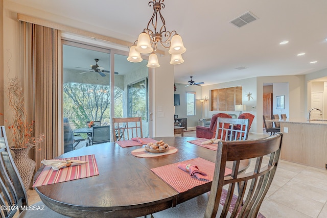 tiled dining area featuring ceiling fan with notable chandelier and sink