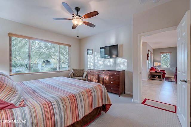 bedroom featuring ceiling fan, light carpet, and multiple windows