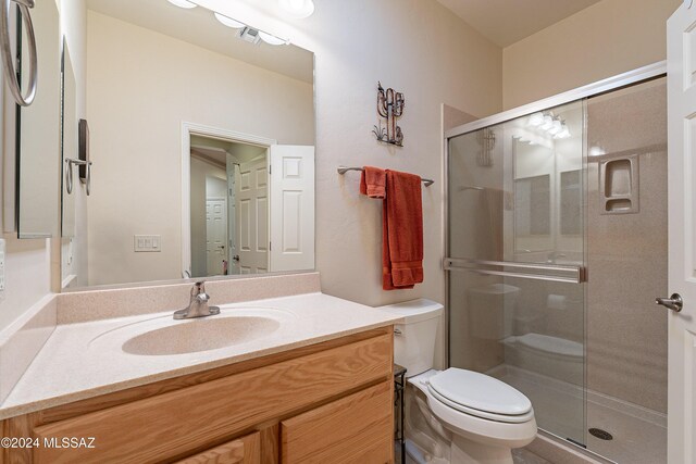 bathroom with vanity, toilet, and a shower with door