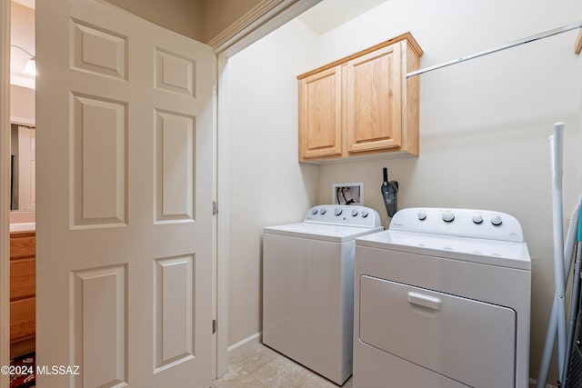 clothes washing area featuring cabinets, light tile patterned floors, and washing machine and dryer