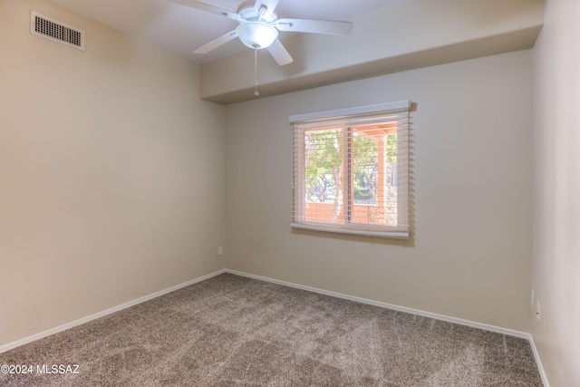 carpeted empty room featuring baseboards, visible vents, and a ceiling fan