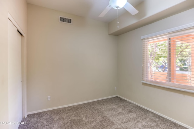 carpeted empty room featuring baseboards, visible vents, and a ceiling fan