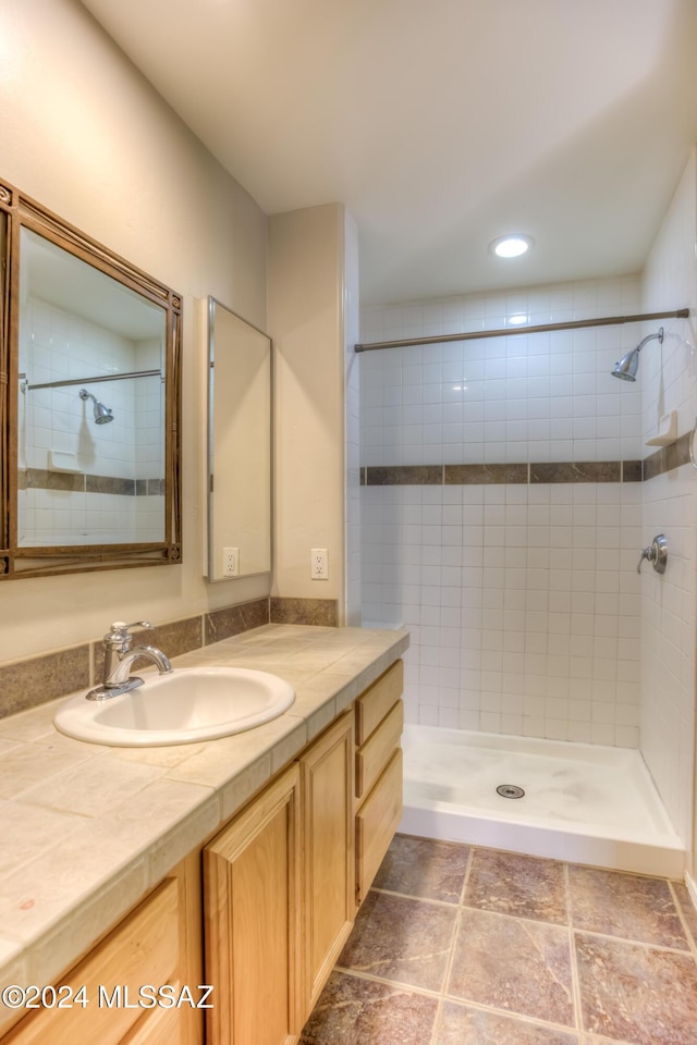 bathroom with tiled shower and vanity