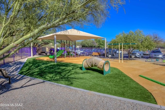 community jungle gym featuring fence and a lawn