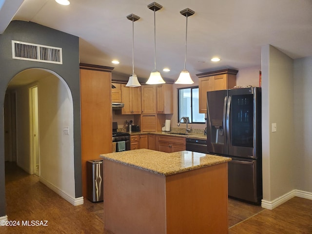 kitchen with black appliances, decorative light fixtures, a center island, and dark hardwood / wood-style flooring