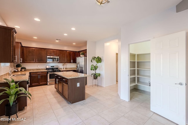 kitchen featuring a center island, sink, stainless steel appliances, light stone counters, and light tile patterned floors