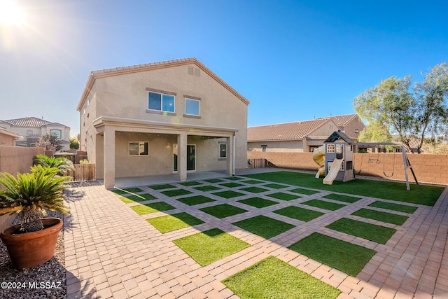 rear view of property with a playground, a patio area, and a yard